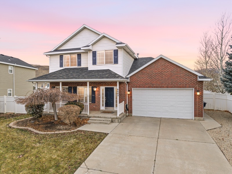 Herriman Retreat, a two-story family home with a covered porch at sunset